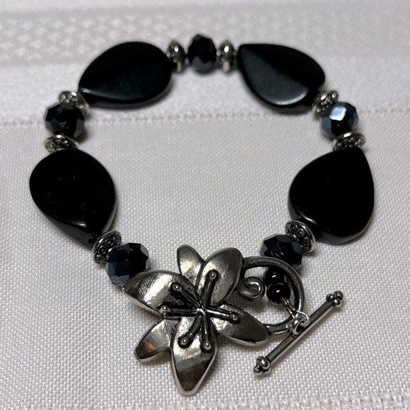 Black beaded bracelet with unique flower clasp. Clasp closure is Silvertone. - Picture 1 of 4